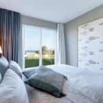 Schlafzimmer mit Bett, Fenster und Wandbild mit Fischen.