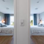 Zwei Schlafzimmer mit Betten, Vorhängen und Fenstern zur Aussicht.