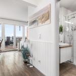 Wohnbereich mit Balkon und Badezimmer mit Dusche und Waschbecken.