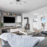 Wohnzimmer mit Sofa, Kamin und Fernseher. Küche und Essbereich im Hintergrund.