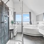 Badezimmer mit Dusche, Badewanne und Fensterblick auf Hafen