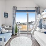 Schlafzimmer mit Doppelstockbett, Sofa und Balkon mit Meerblick.
