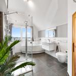 Badezimmer mit Badewanne, Dusche und Sauna. Große Fenster mit Meerblick.