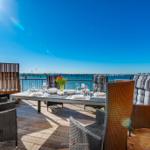 Terrasse mit Esstisch, Stühlen und Grill direkt am Wasser.