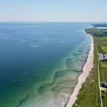 Aerielansicht einer Küstenlandschaft mit Strand, Meer und grünen Feldern
