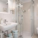 Badezimmer mit Dusche, Waschbecken und Toilette. Handtücher in Körben.