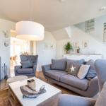 Wohnzimmer mit Sofa, Sessel und Kamin. Wanddekoration und Tisch mit Fischfigur.