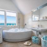 Badezimmer mit Badewanne, Waschmaschine und Blick aufs Meer.