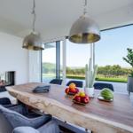 Essbereich mit Holztisch, Stühlen und Blick auf die Landschaft.