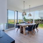 Essbereich mit Holztisch, dunklen Stühlen und Blick auf Grünland.
