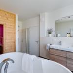 Bad mit Whirlpool, Dusche und Sauna. Holzwände und Waschtisch mit Spiegel.