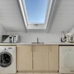Kitchen with washing machine, dryer, sink, and skylight.