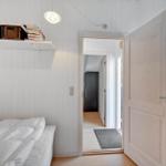 Bedroom with white bed, wooden wall, and door to hallway.