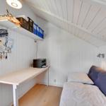 Bedroom with desk, bed, and shelf on the wall.