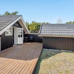 Wooden cabin with terrace and garden. White door and windows. Roof with shingles.