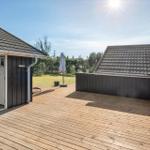 Wooden terrace with view of lawn and houses. Sunny day with shadows cast.