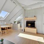 Living and dining area with wooden floor, skylights, and wood stove.