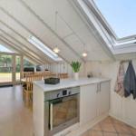 Kitchen with dining area under roof with large skylight and view of garden.