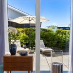 Through large windows, a terrace with loungers and umbrella is visible.