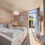 Bedroom with wooden wall, bed, and view of terrace.