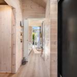 Hallway with wooden walls, closet, and view into living area.