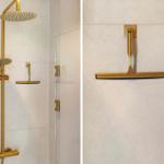 Shower cabin with gold fixtures and glass wall.
