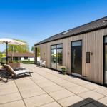 Modern wooden house with large terrace and sun protection.
