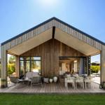 Modern wooden cabin with covered deck, seating, and view into the kitchen.