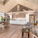 Living area with dining space, kitchen, and balcony. Wooden ceiling and floor.