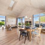Spacious room with wooden ceiling, dining table, and large windows. View of garden and terrace.