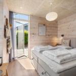 Bedroom with wooden walls, bed, and window to terrace.