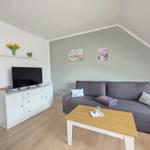 Living room with gray sofa, wooden table, and TV on white cabinet.