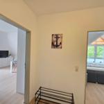Hallway with view into bedroom and living area. Wall art with anchor design.