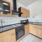 Kitchen with wooden cabinets, stainless steel sink, and cooktop with oven.