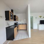 Kitchen with wooden cabinets and countertop. Living room with TV and cabinet.