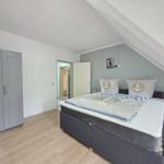 Bedroom with double bed, wardrobe, and nightstand under sloped ceiling.
