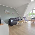 Living and dining area with sofa, dining table, and large window. Wooden floor and gray walls.