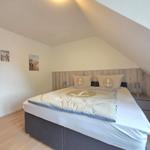 Bedroom with double bed, anchor motif, and wooden wall under sloped ceiling.