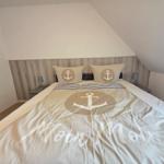 Bedroom with bed, pillows, and bedding featuring anchor motif and Moin Moin text.