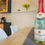 A bottle of alcohol-free white wine sits on a dining table in a kitchen with white chairs.