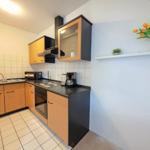 Kitchen with wooden cabinets, stove, sink, and flowers on the wall