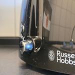 Black toaster with dial knob and brand logo on countertop.