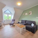 Living room with sofa, coffee table, and rocking chair under sloped ceilings.