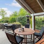 Terrace with table, chairs, grill, and garden view.
