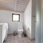 Bathroom with toilet, washing machine, and shower under wooden ceiling.