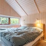 Bedroom with wooden walls, roof window, and bed with cushioned headboard.
