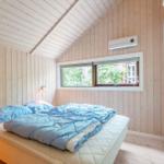 Bedroom with wooden walls, bed, and window. Air conditioner on the wall.