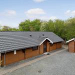 Wooden house with gray roof, garden area, and small garage. Surrounded by trees.
