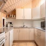 Kitchen with wooden walls, light cabinets, sink, and refrigerator.
