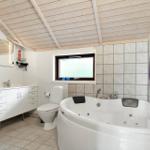 Bathroom with jacuzzi, toilet, and sink under wooden ceiling.
